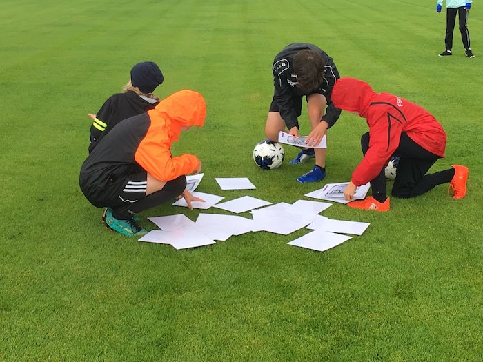Mädchen sitzen im Kreis mit Trainer und besprechen die Taktik im Fußballcamp für Mädchen