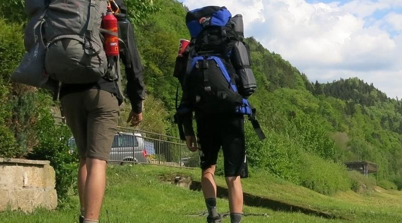 Zwei Teilnehmer eines Trekkingcamps wandern mit Rucksäcken durch die Natur