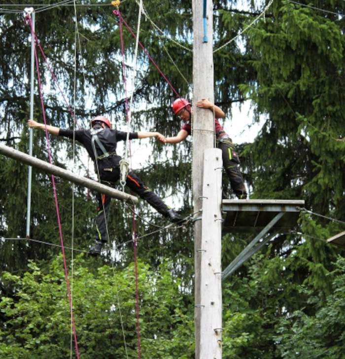 Zwei Teilnehmer des Ferienlager Innsbruck sind in einem Hochseilgarten