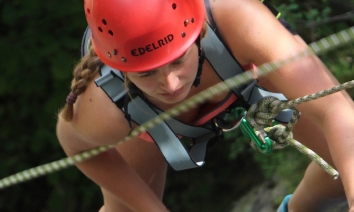 Mädchen klettert mit Sicherheitsgurt in einem Hochseilgarten