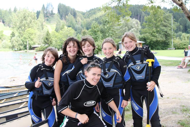 Die Teilnehmer des Englisch-Camps Allgäu tragen Neoprenanzüge und grinsen in die Kamera