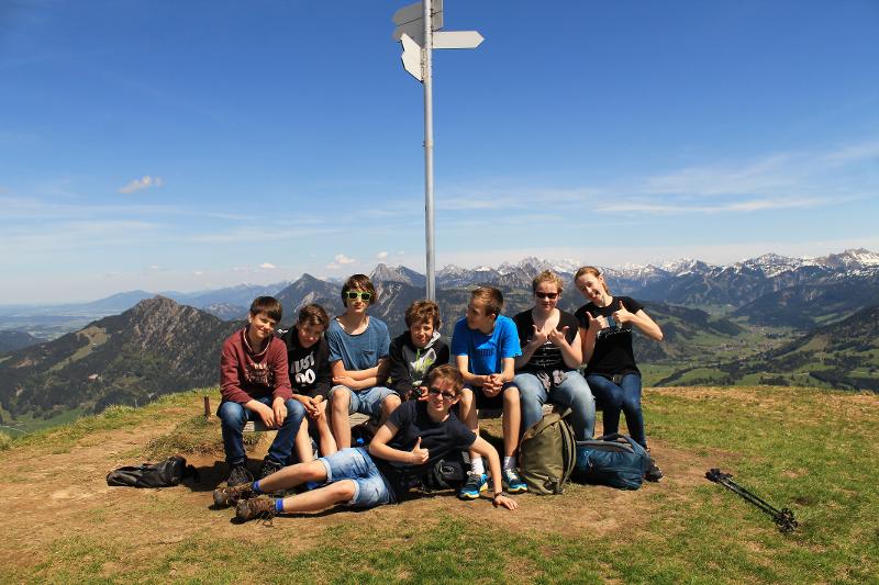 Im Ferienprogramm Osterferien sitzen die Kinder auf einer Bergspitze und machen eine Pause