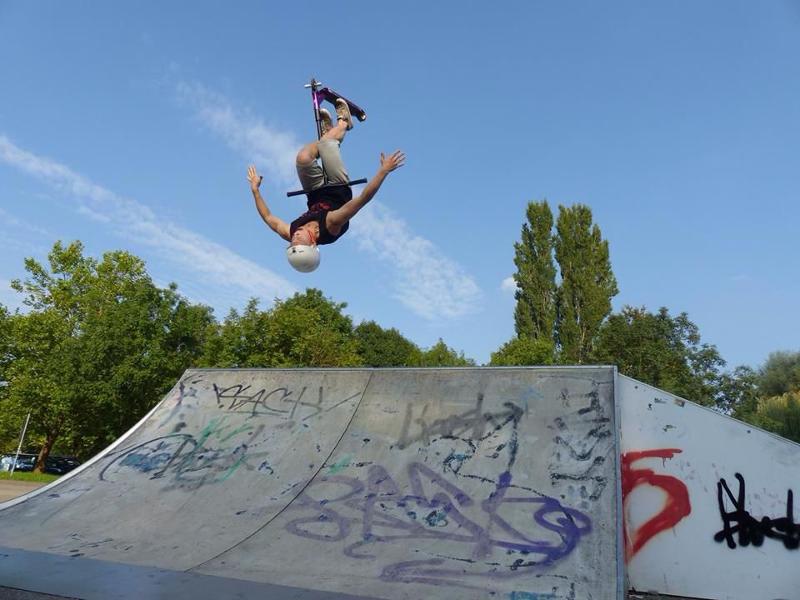 Junge übt auf einer Strecke einen Backflip mit seinem Scooter
