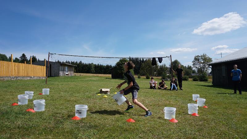 Ein Junge rennt bei einem Spiel auf einer Wiese mit Bällen hin und her mit