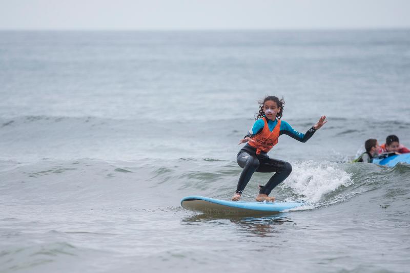 Mädchen steht auf Surfbrett im Surf-Camp in Portugal