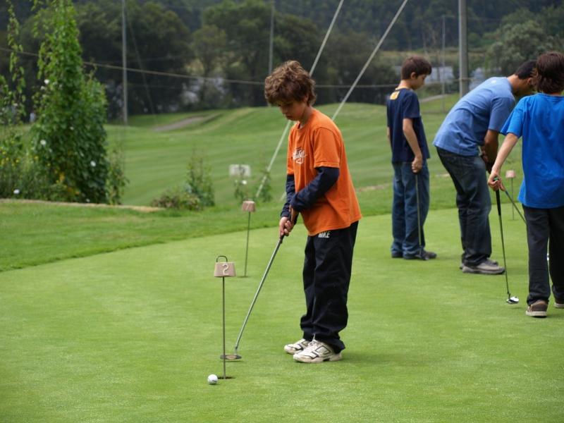 Junge spielt Golf in den internationalen Reiterferien Portugal