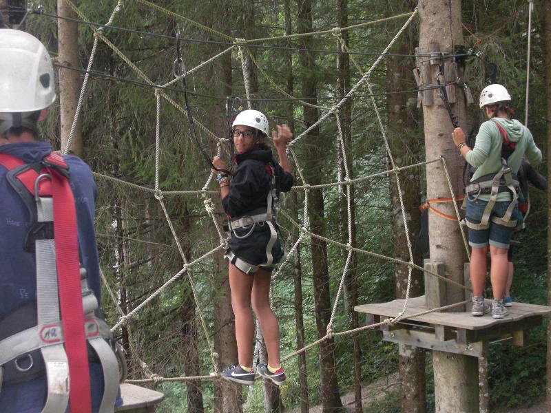 Ein Mädchen des Feriencamp Graz klettert in einem Hochseilgarten durch ein Spinnennetz aus Seilen