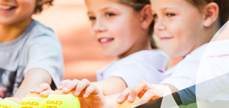 Drei Kinder greifen nach Tennisbällen in ihren Lern-Ferien