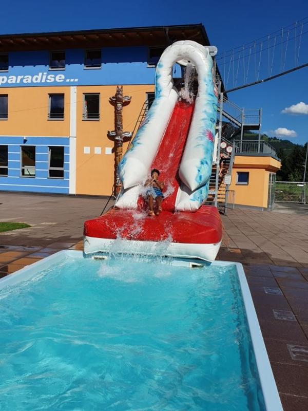 Ein Teilnehmer des Englisch-Camps Wien rutscht eine Rutsche hinunter in einen Pool