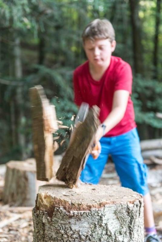 Junge hackt Holz im Abenteuerurlaub Kinder Österreich