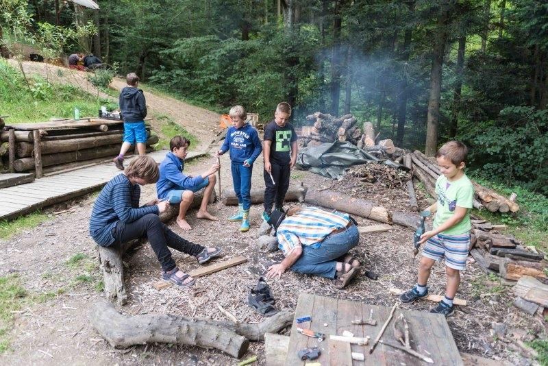 Eine Kindergruppe schnitz Holstücke im Mischwald während der Ferienbetreuung Stadt Wien