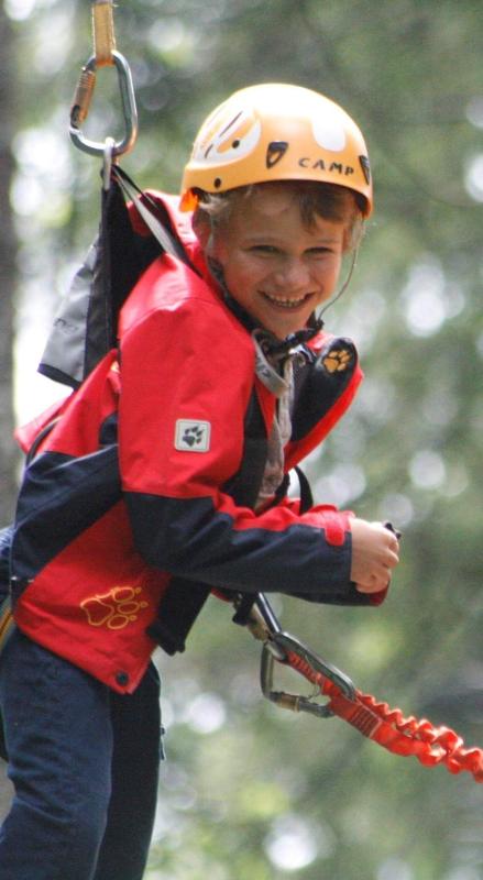 Junge hängt in der Luft im Hochseilgarten im Sommercamp für Kinder