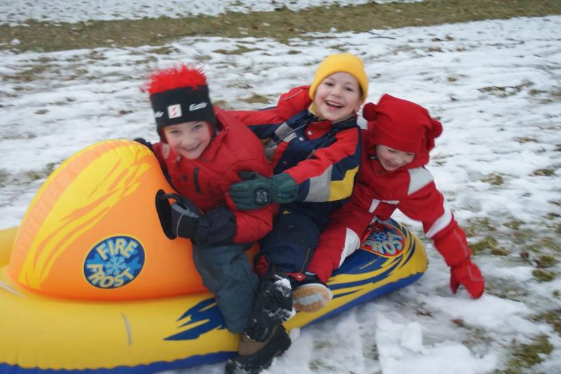 Drei Jungs rodeln im Winter-Camp für Kinder