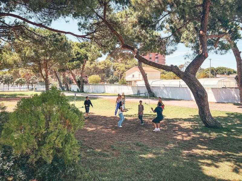 Jugendliche spielen im Schatten der Bäume Volleyball bei den Surfcamps Lissabon