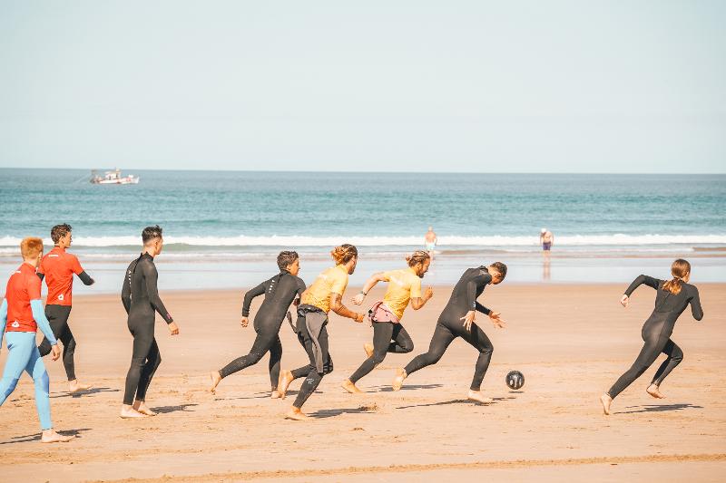  Eine Gruppe Jugendlicher spielt am Stand Fußball bei den Surfcamps Lissabon