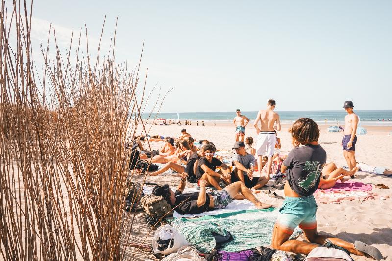 Jugendliche liegen auf ihren Handtüchern und entspannen am Strand bei den Surfcamps Lissabon