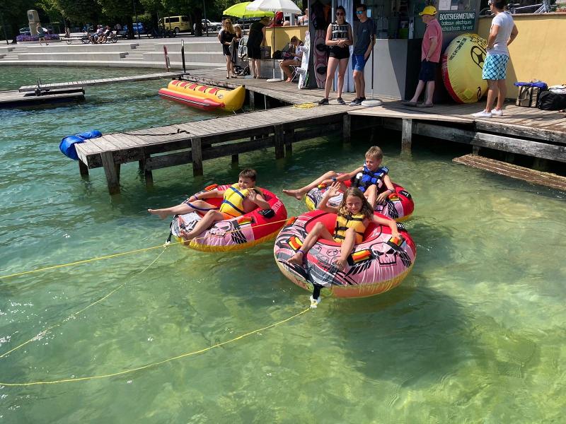 Drei Kinder sitzen im Wolfgangsee auf ihren Wasserreifen 