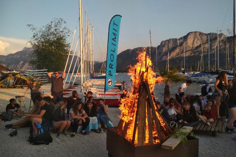 Teilnehmer sitzen am Lagerfeuer im Ferienlager am See