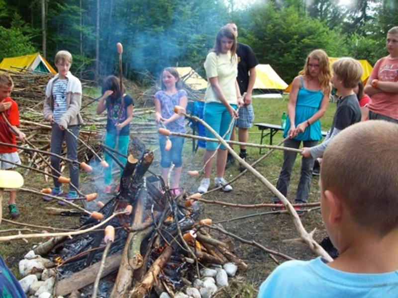 Die Kinder des Feriencamp Graz grillieren Knacker an einem Lagerfeuer