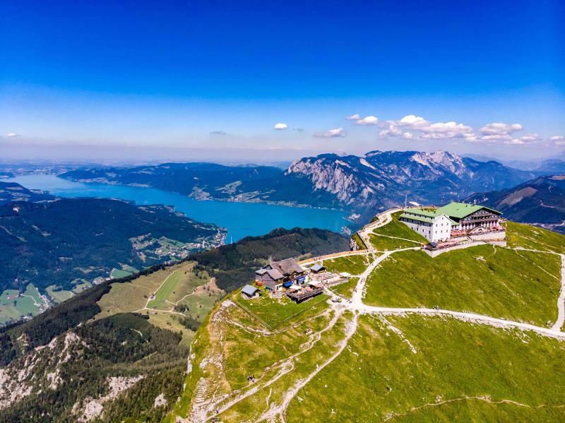 Zwei Hütten auf der Spitze eines Berges mit dem Attersee im Hintergrund im Sommercamp Attersee