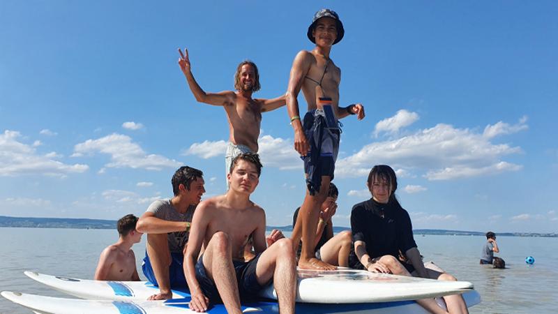 Jungs sitzen auf ihren Surfbretten im Surfcamp Neusiedlersee