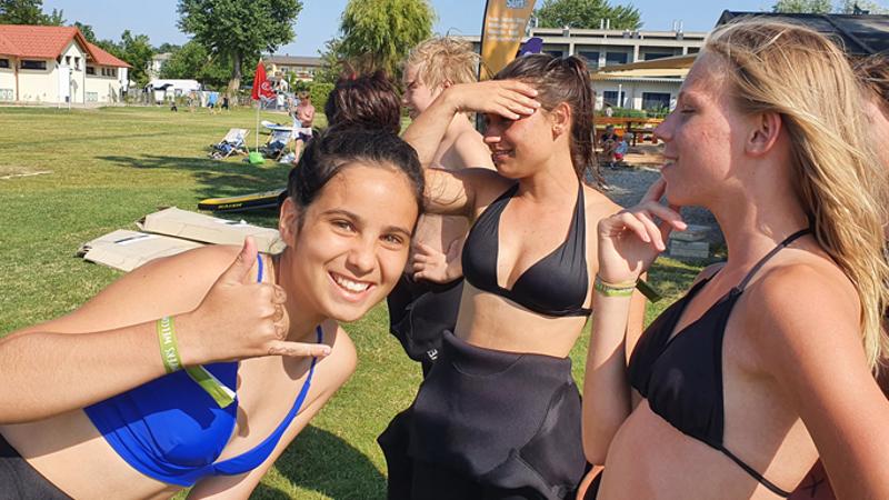 Ein Mädchen in Biki steht auf einer Badewiese und lächelt in die Kamera