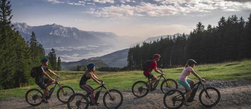 Eine Gruppe Kinder fährt über einen Feldweg in der Abenddämmerung im Sommercamp Kinder