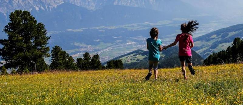 Zwei Mädchen rennen über eine Wiese im Englisch-Camp Tirol