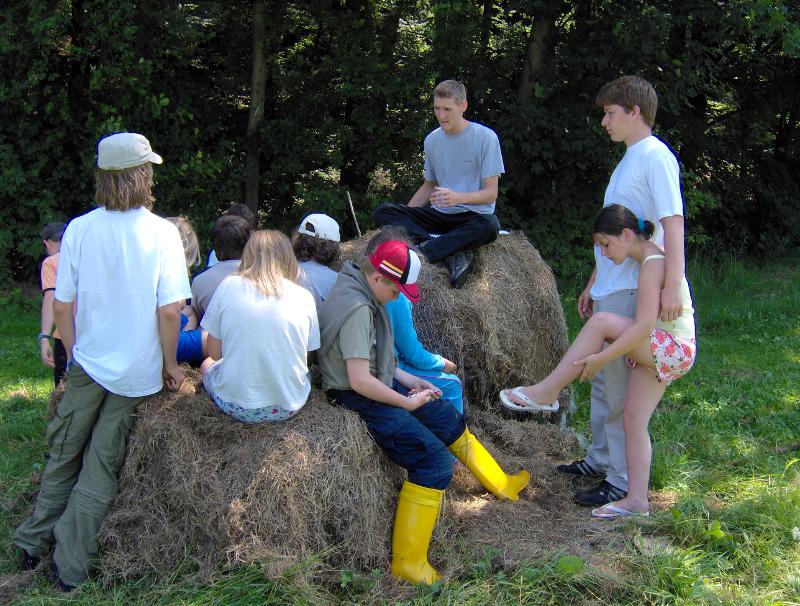 Die Kinder und Jugendlichen des Offline-Camps sitzen auf Strohballen und unterhalten sich