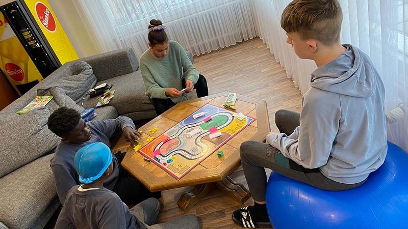 Im Feriencamp Deutsch lernen spielen die Teilnehmer ein Brettspiel im Gemeinschaftsraum