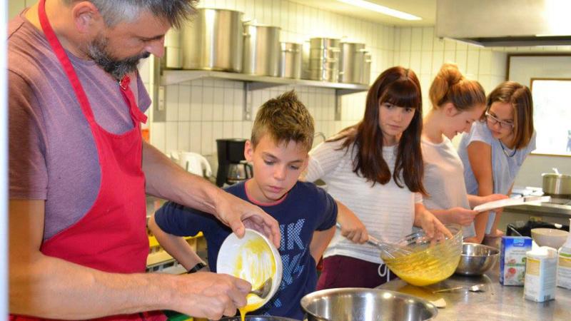 Die Kinder in der Ferienbetreuung Ostern stehen in der Küche und lernen kochen