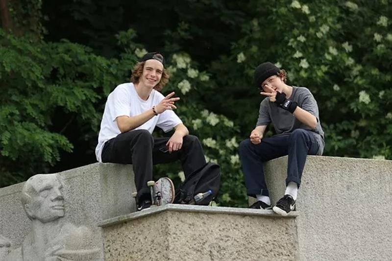 Zwei Jungen die Skateboard fahren machen gerade eine Pause und sitzen auf einem Steinblock