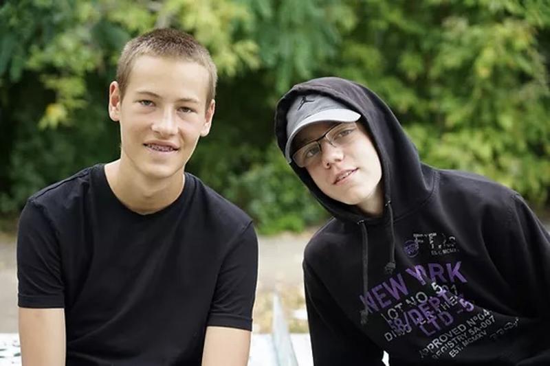 Zwei Freunde sitzen draußen und schauen zum Kameramann
