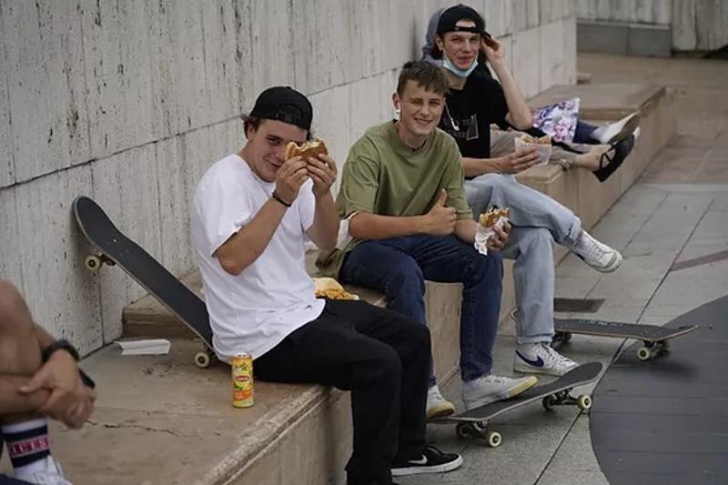 Mehrere Jungs sitzen auf Steinen und essen Burger