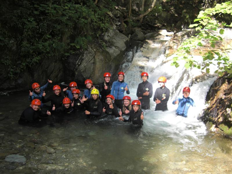 Mehrere Teilnehmer des Actioncamps stehen unter einem Wasserfall