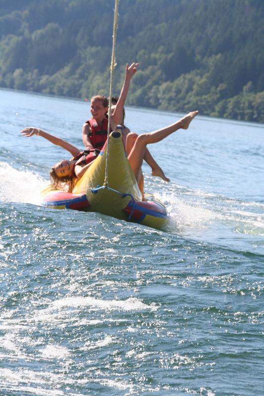 Mädchen lassen sich auf einem Bananenboot im Actioncamp Mölltal über das Wasserziehen
