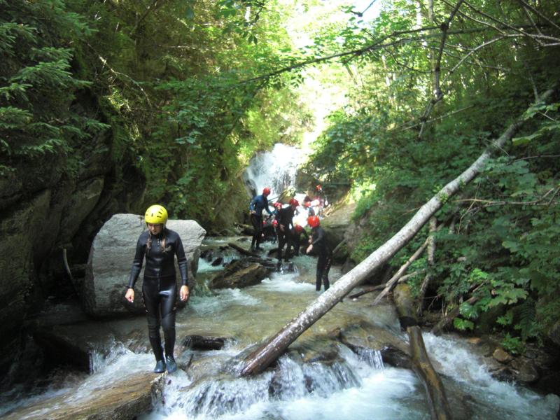 Die Teilnehmer des Actioncamps Mölltal wandern im Fluss mit Neoprenanzügen