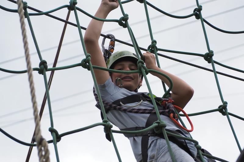 Ein Junge klettert an einem Netzt aus Seilen entlang im Actioncamp