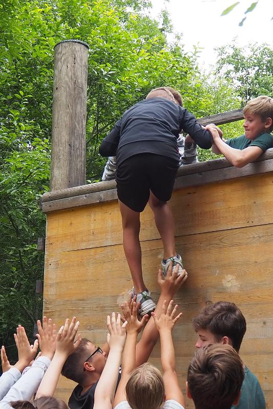 Die Teilnehmer des Actioncamps helfen einander um über eine Holzwand zu klettern