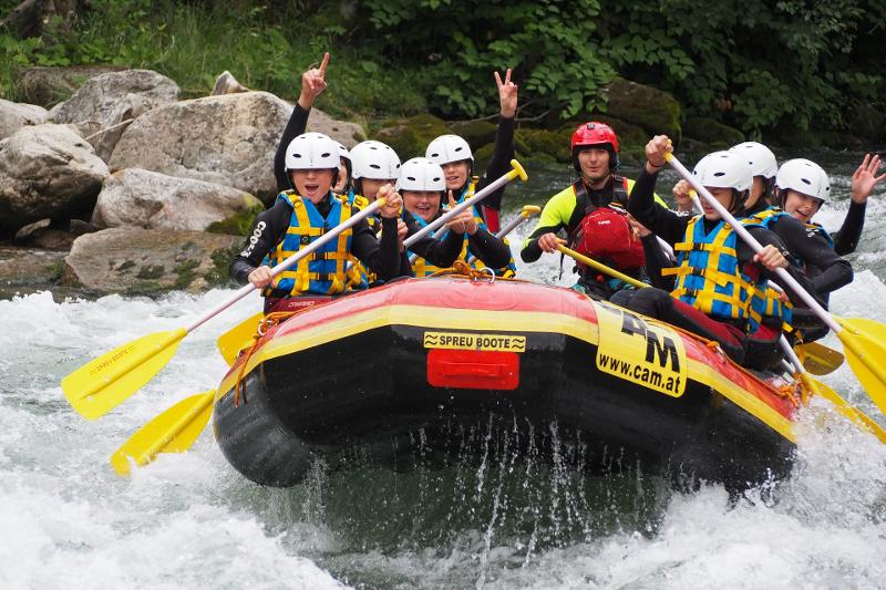 Kindergruppe beim Wildwasser Rafting während eines Sommer-Camps