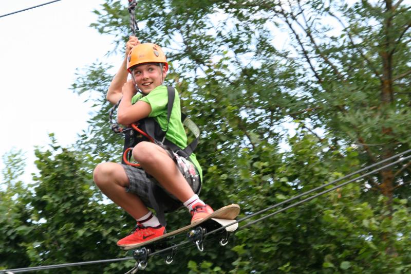 Junge hängt an einer Seilbahn und hat Spaß im Sommer-Camp