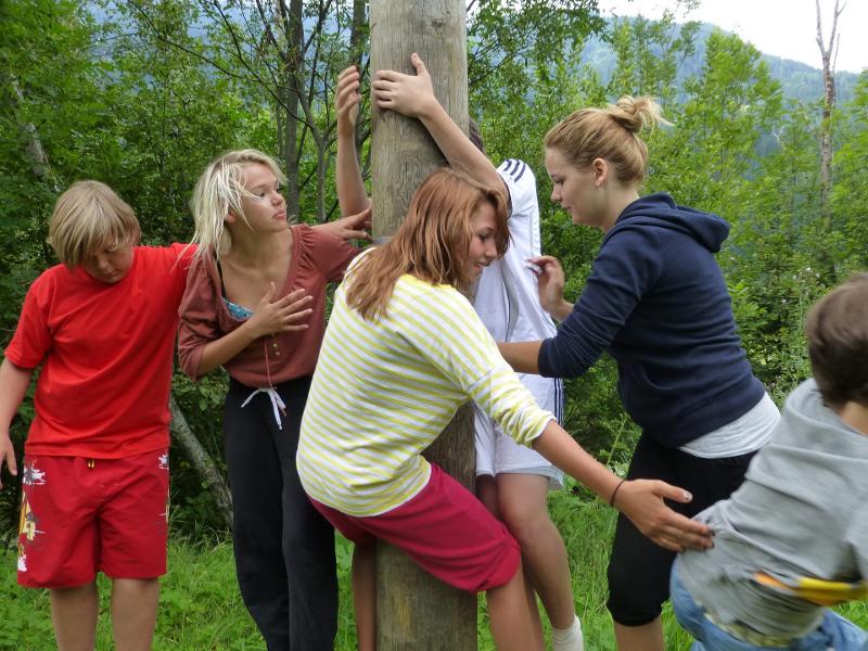 Die Teilnehmerinnen eines Sommercamps klettern einen Holzmast hinauf