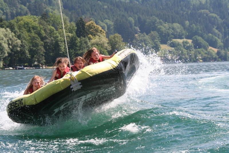 Die Kinder werden im Actioncamp auf großen Reifen über das Wasser gezogen und haben dabei viel Spaß