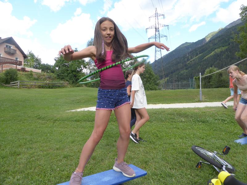 Mädchen schwingt ihren Hulahoop Reifen um ihre Hüfte während des Sommercamps