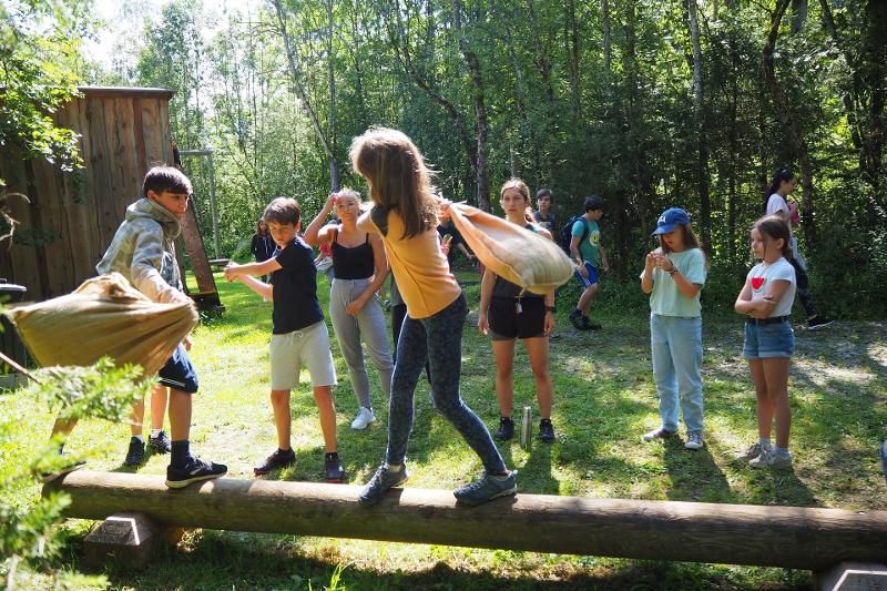 Zwei Teilnehmer des Englisch-Camps balancieren auf einem Baumstamm und versuchen einander umzustoßen