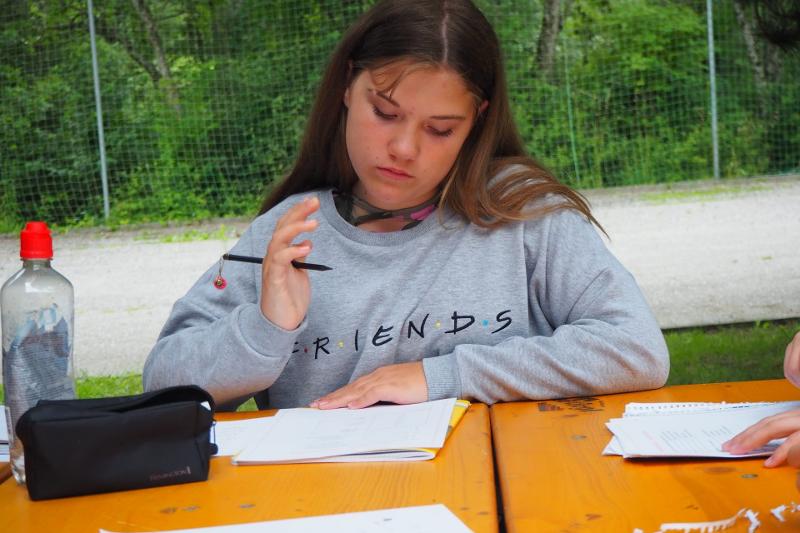 Ein Mädchen schreibt im Englisch-Camp mit Stiften auf ihren weißen Papierblöcken