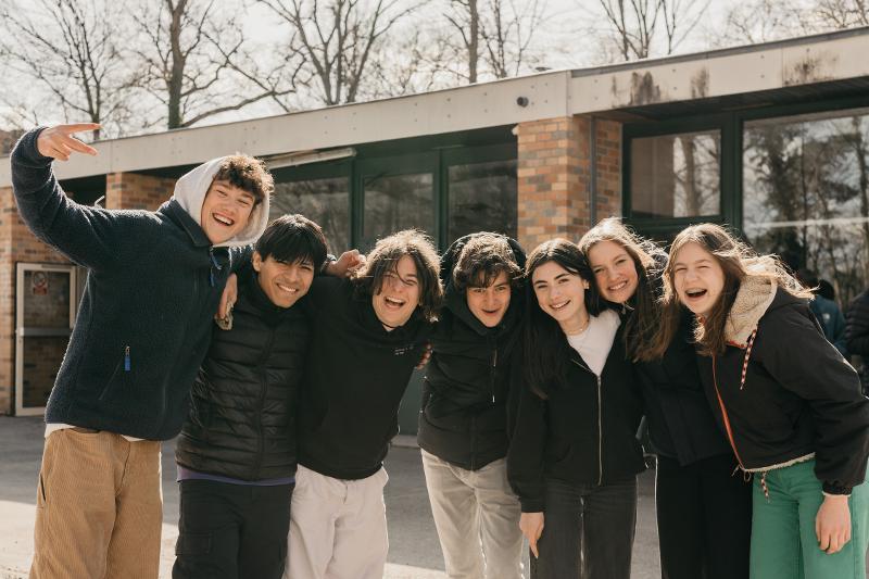 Eine Gruppen Jugendlicher lachen legen die Arme über die Schulter während ihrer Sprachreise Belgien 