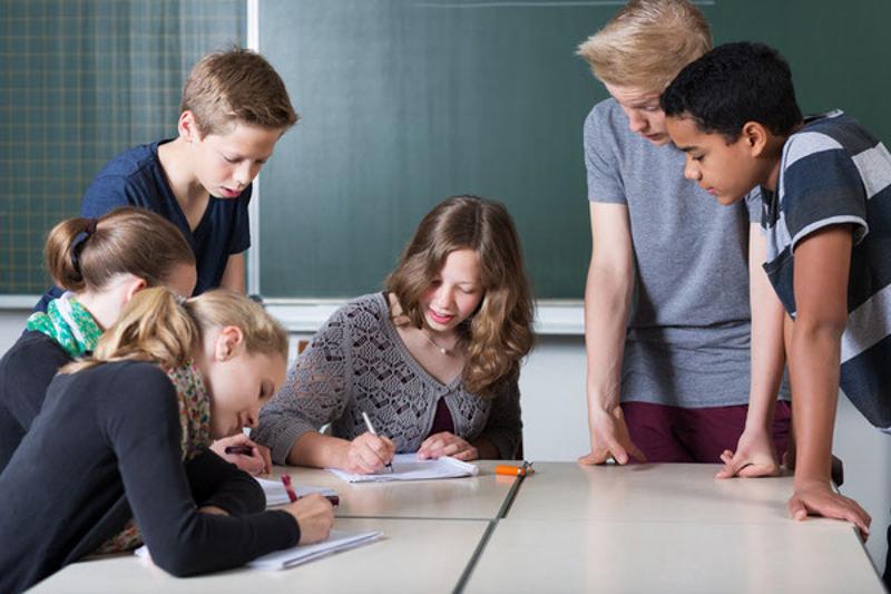 Im Feriencamp Krems sitzen die Teilnehmer an Tischen und schreiben auf Papier um ihr Wissen zu erweitern