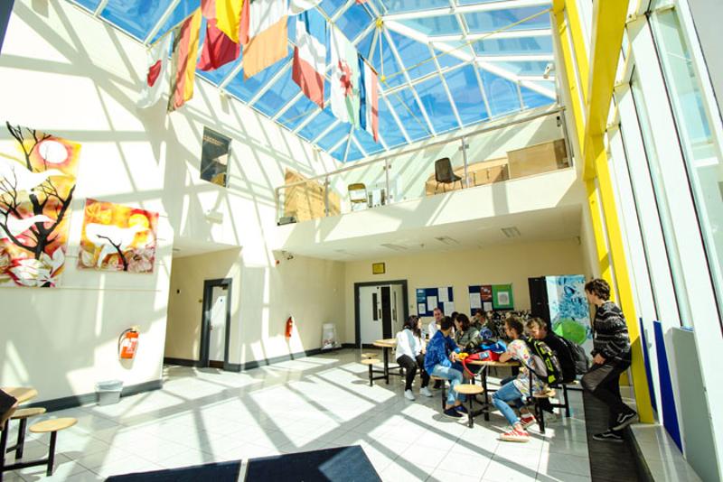 Schüler sitzen während der Sprachreise Irland Dublin im lichtdurchfluteten Atrium der Sprachschule