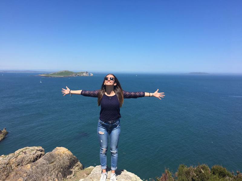 Auf der Irland Sprachreise steht eine Teilnehmerin an der Klippe und geniesst die Sonne